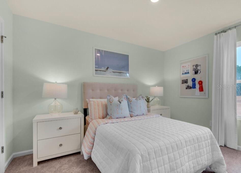 A bedroom features a bed with a tufted headboard, two nightstands, and light blue walls — 444 PATRICIA ALFORD DRIVE, HAINES CITY, FL