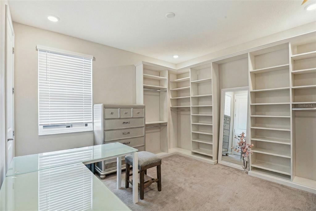 A modern kitchen features white cabinetry, a central island with bar stools, and wood-look flooring — 5026 TIVOLI DRIVE, WESLEY CHAPEL, FL
