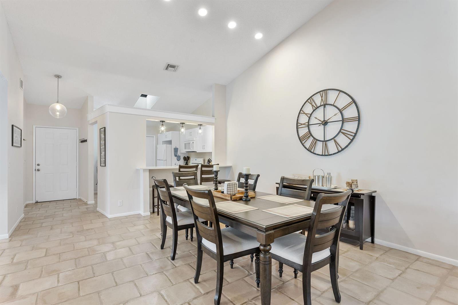 A dining room features a dark wood table, matching chairs, and a large wall clock — 5861 Sunswept Lane # B, Boynton Beach FL 33437, BOYNTON BEACH, FL