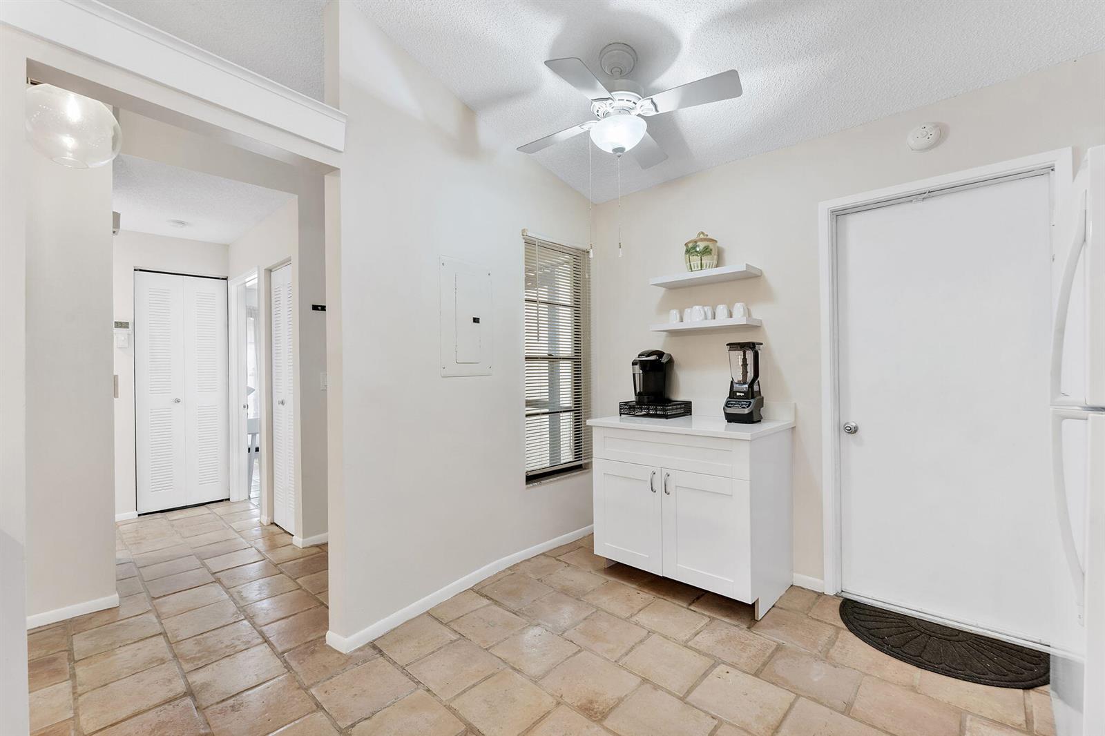 A kitchen area features tile flooring, a white cabinet, floating shelves, and a ceiling fan — 5861 Sunswept Lane # B, Boynton Beach FL 33437, BOYNTON BEACH, FL