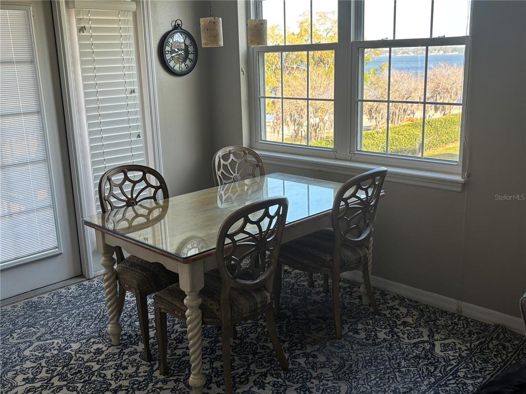 A dining area features a glass-topped table, four patterned chairs, and a view of water — 152 NAUTICA MILE DRIVE, CLERMONT, FL