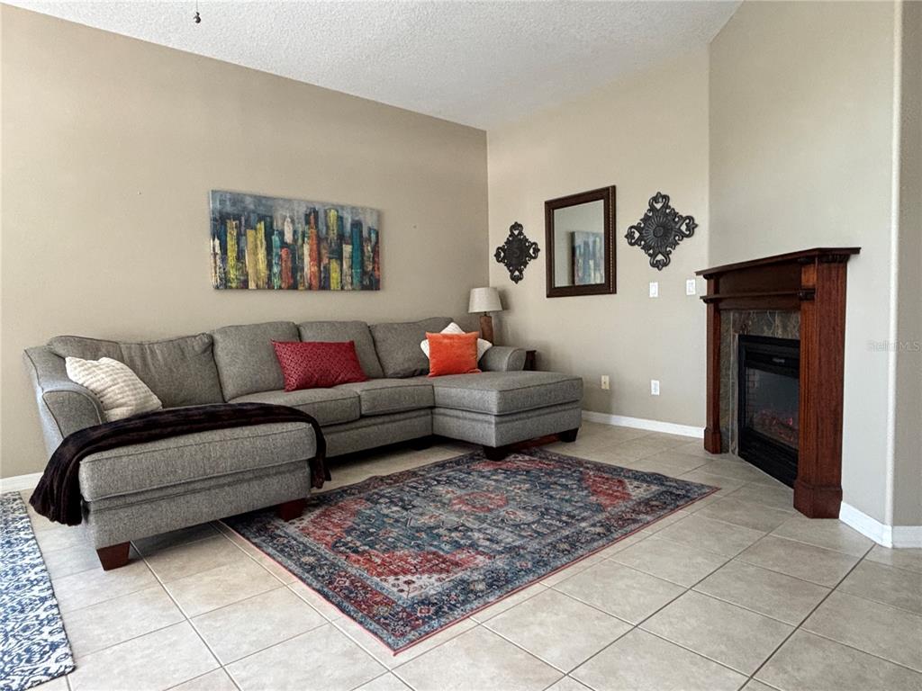 A living room features a gray sectional sofa, a patterned area rug, and a fireplace — 152 NAUTICA MILE DRIVE, CLERMONT, FL