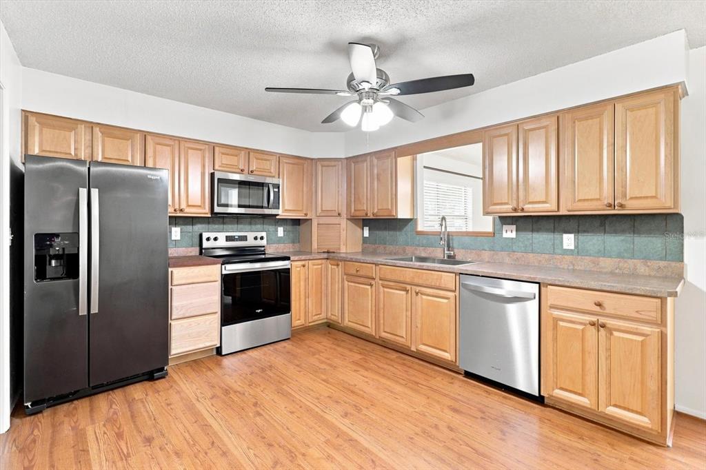 A kitchen features wood cabinets, stainless steel appliances, a ceiling fan, and wood-look flooring — 1285 N HAGGERTY POINT, CRYSTAL RIVER, FL