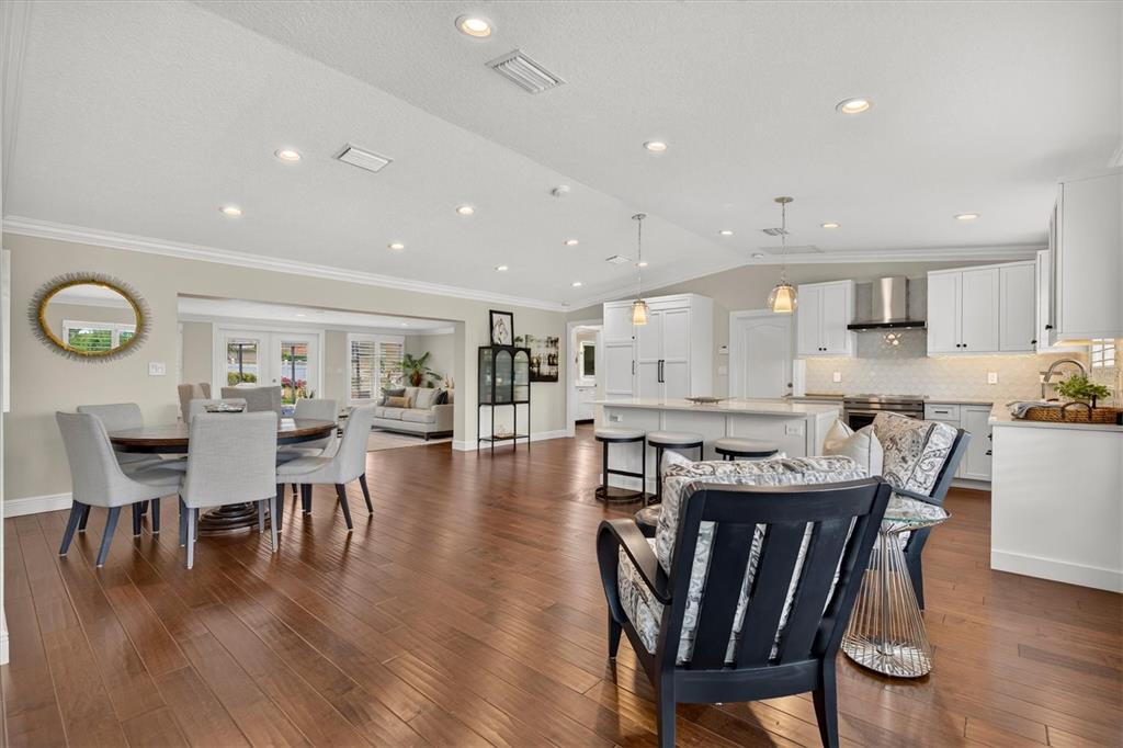 An open-concept kitchen and dining area features white cabinetry, hardwood floors, and recessed lighting — 802 OSCEOLA ROAD, BELLEAIR, FL
