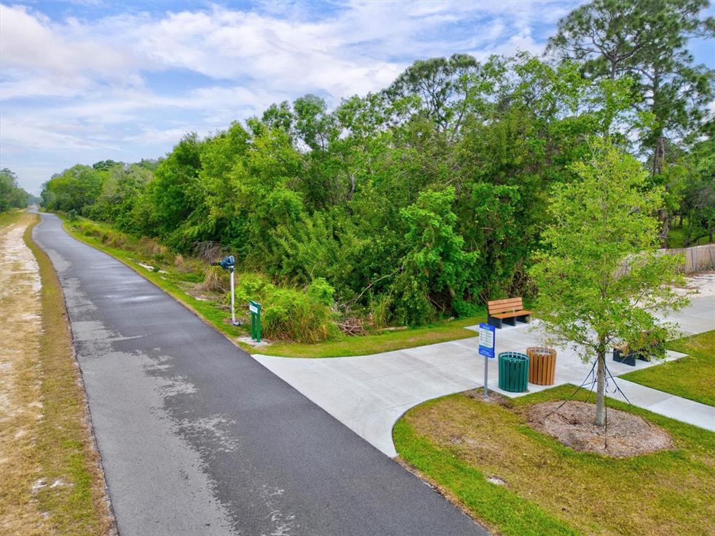 An asphalt trail runs alongside a concrete rest area with a bench and trash cans — 3210 WOOD STREET, SARASOTA, FL