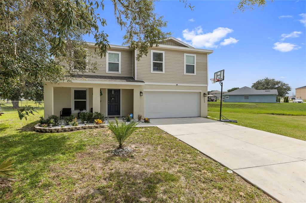 A two-story house with beige siding, a front porch, and a two-car garage — 1889 SNAPPER DRIVE, POINCIANA, FL