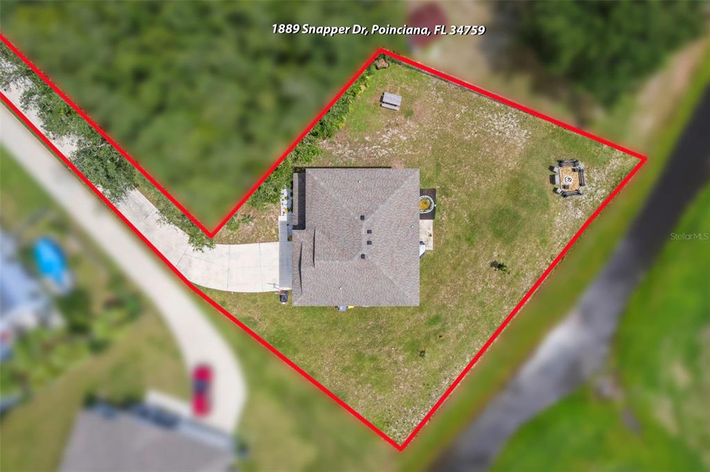 An aerial view shows a house with a large yard outlined in red — 1889 SNAPPER DRIVE, POINCIANA, FL