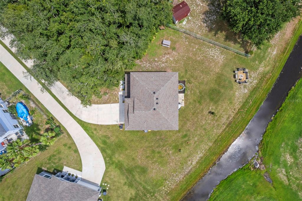 An aerial view shows a house with a driveway, a backyard, and a drainage canal — 1889 SNAPPER DRIVE, POINCIANA, FL