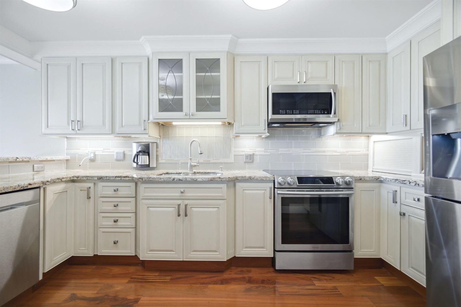 A kitchen with off-white cabinets, stainless steel appliances, granite countertops, and hardwood flooring — 2901 S Palm Aire Drive, Pompano Beach FL 33069, POMPANO BEACH, FL