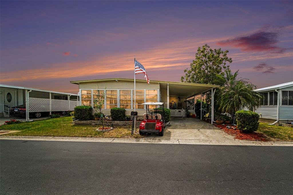 A single-story manufactured home with a carport, a golf cart, and an American flag — 12501 ULMERTON ROAD UNIT 33, LARGO, FL
