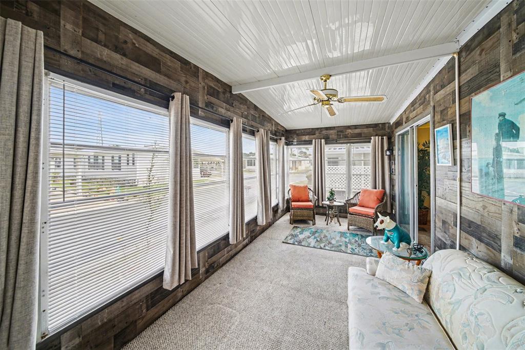 A sunroom features wood-plank walls, a white ceiling with a fan, and large windows — 12501 ULMERTON ROAD UNIT 33, LARGO, FL