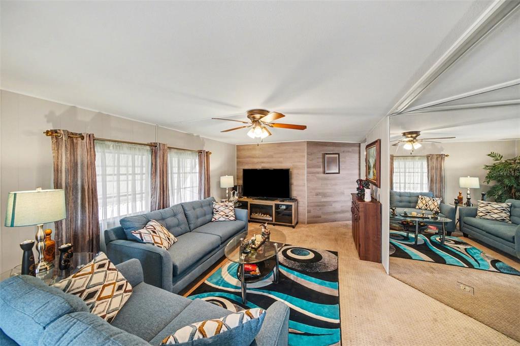 A living room features blue sofas, a patterned area rug, and a mirrored wall — 12501 ULMERTON ROAD UNIT 33, LARGO, FL