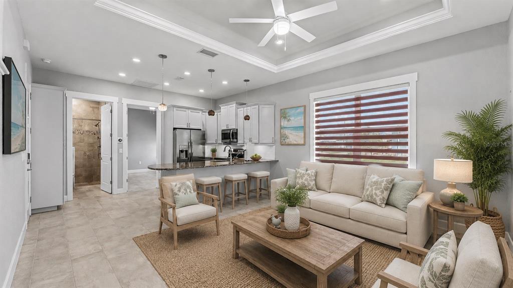 A bright living room with a tray ceiling, neutral furniture, and an open-concept kitchen — 3220 FISH HAWK DRIVE, POLK CITY, FL