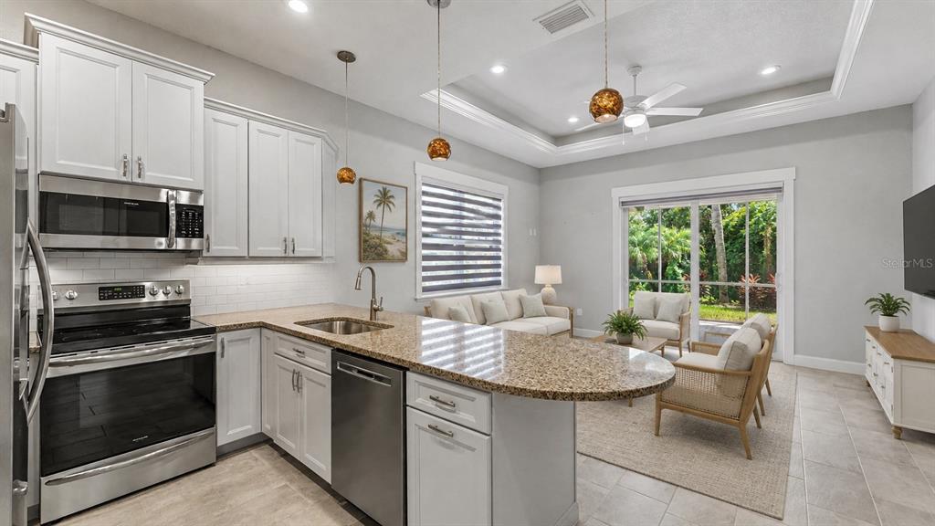 A kitchen with white cabinets and granite countertops opens into a living area with patio doors — 3220 FISH HAWK DRIVE, POLK CITY, FL
