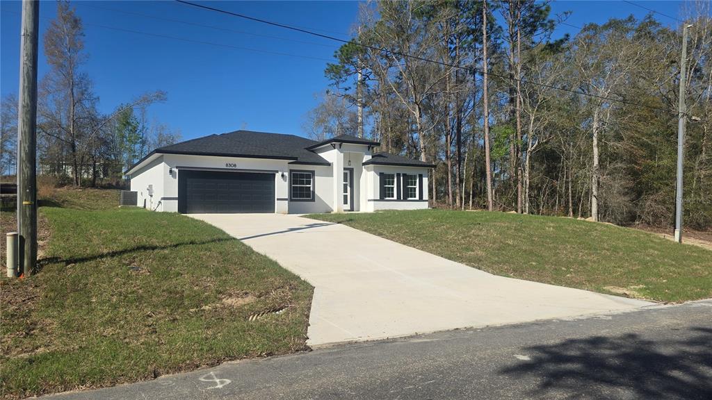 A single-story house with a white exterior, black roof, and a two-car garage — 8308 N VINCE DRIVE, CITRUS SPRINGS, FL