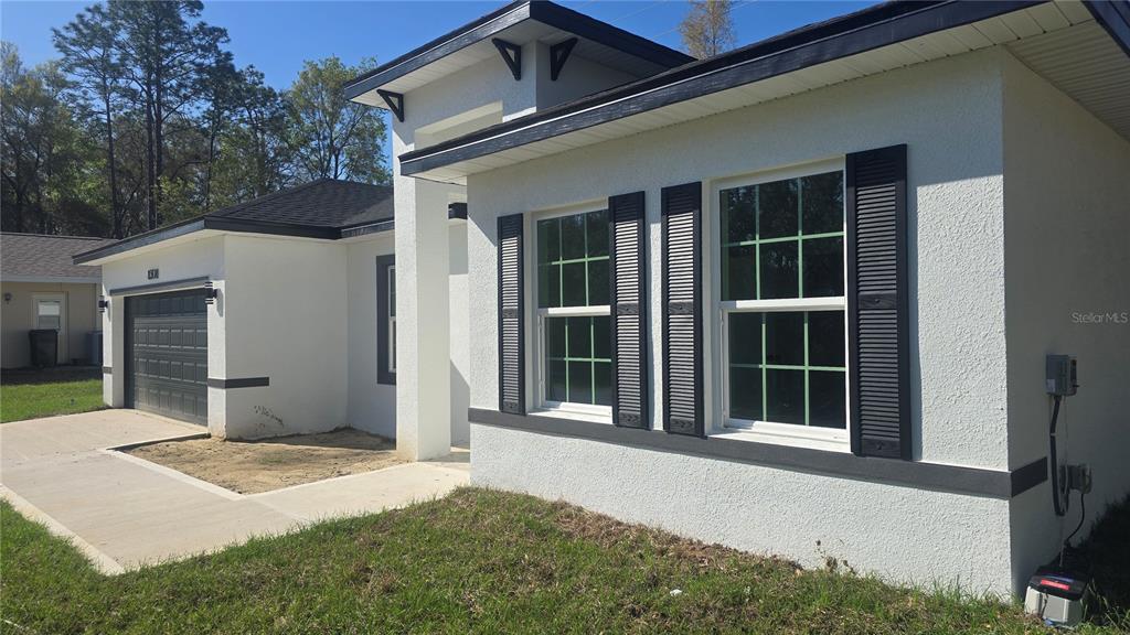 A white stucco house with black trim, a garage, and two windows with black shutters — 8308 N VINCE DRIVE, CITRUS SPRINGS, FL