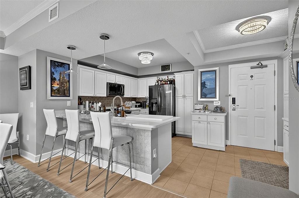 A kitchen features white cabinets, a marble-topped island with bar seating, and tile flooring — 200 OCEAN CREST DRIVE UNIT 1018, PALM COAST, FL