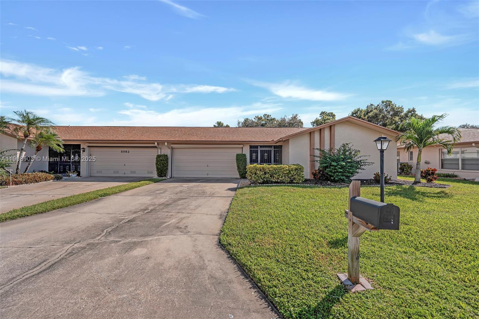 A single-story house features a two-car garage, a concrete driveway, and a front lawn — 5584 Buring Ct, Fort Myers FL 33919, FORT MYERS, FL