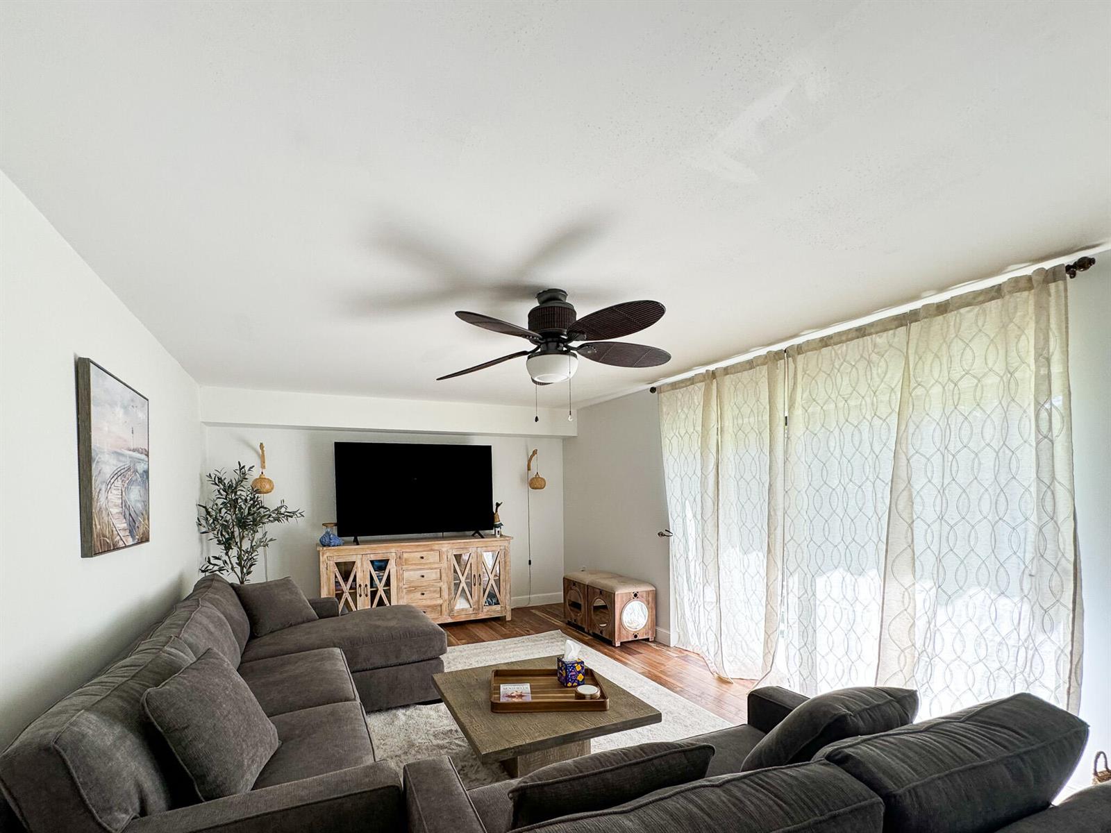 A living room features a gray sectional sofa, a wooden media console, and floor-to-ceiling curtains — 2821 28th Court, Jupiter FL 33477, JUPITER, FL