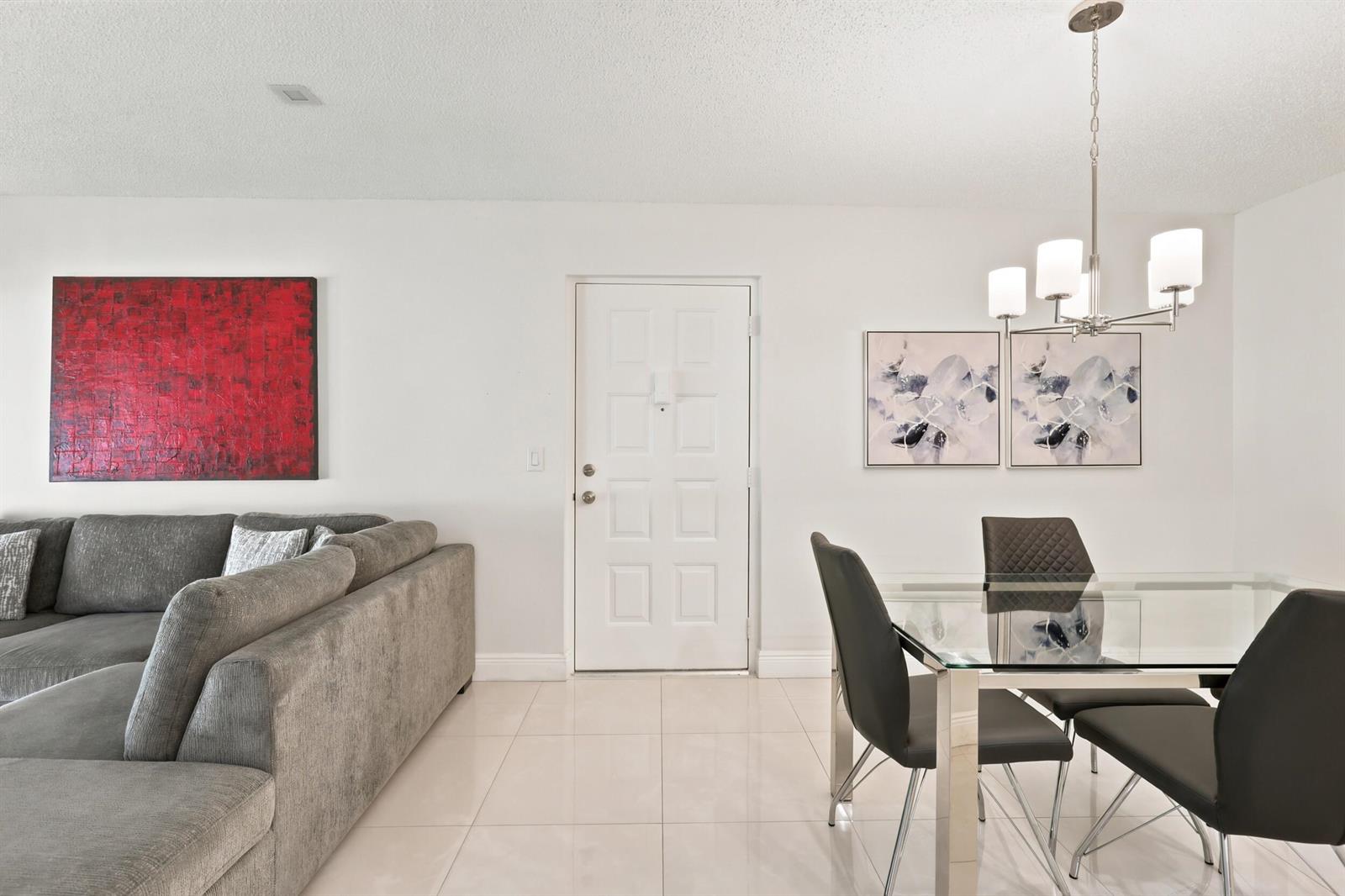 A living and dining area features a gray sectional sofa, glass table, and white tile floors — 609 Sea Pine Way # F2, FL 33415, FL