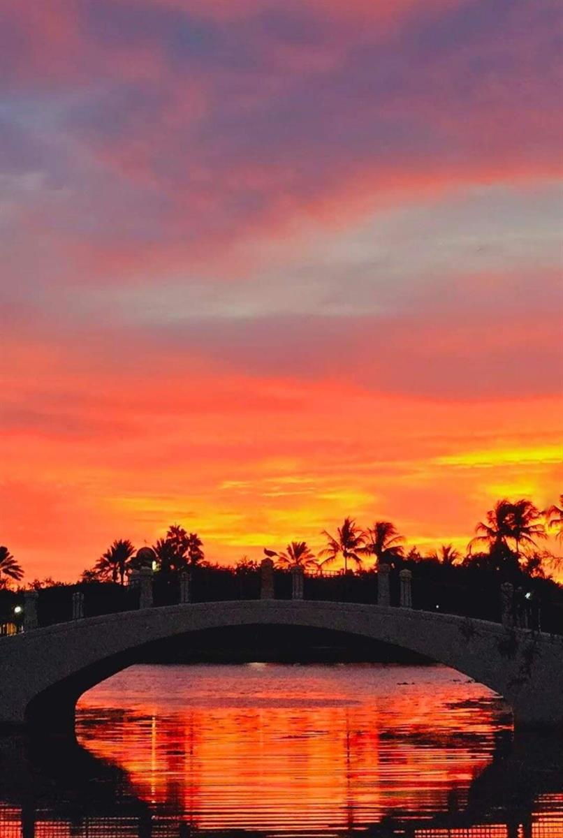 A stone arched bridge spans a calm body of water under a vibrant sunset sky — 8093 Montserrat Place, Wellington FL 33414, WELLINGTON, FL