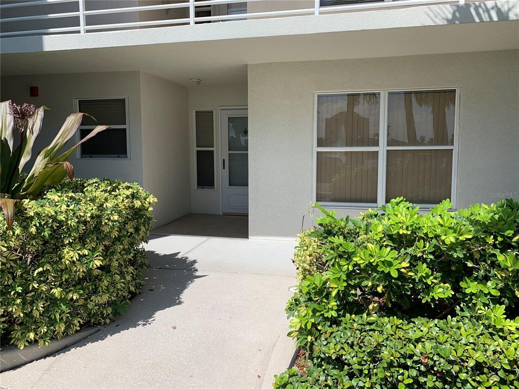 A concrete walkway leads to the front entrance of a building with light-colored exterior walls — 6061 BAHIA DEL MAR CIRCLE UNIT 146, ST PETERSBURG, FL