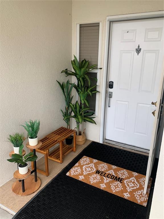 A covered entryway features a white door, a wooden bench, potted plants, and a welcome mat — 6061 BAHIA DEL MAR CIRCLE UNIT 146, ST PETERSBURG, FL