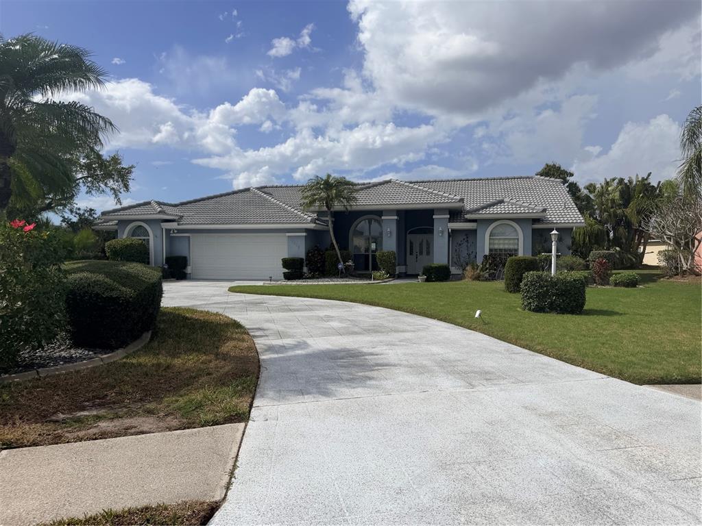 A single-story house with a gray tile roof, white garage, and a curved concrete driveway — 6617 SEVEN PINES DRIVE, BRADENTON, FL