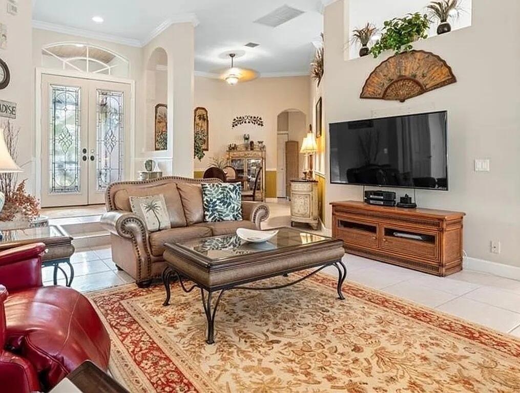 A living room features a leather sofa, glass-top coffee table, and a wall-mounted television — 4204 Abington Woods Circle, Vero Beach FL 32967, VERO BEACH, FL