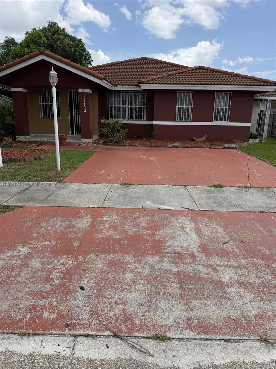 A single-story house with a red-painted driveway and brown exterior walls under a tiled roof — 13752 SW 156th St, Miami FL 33177, MIAMI, FL