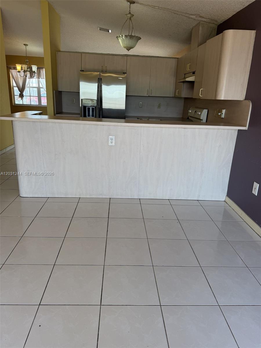 A kitchen features light wood-look cabinets, stainless steel appliances, and a tiled floor — 13752 SW 156th St, Miami FL 33177, MIAMI, FL