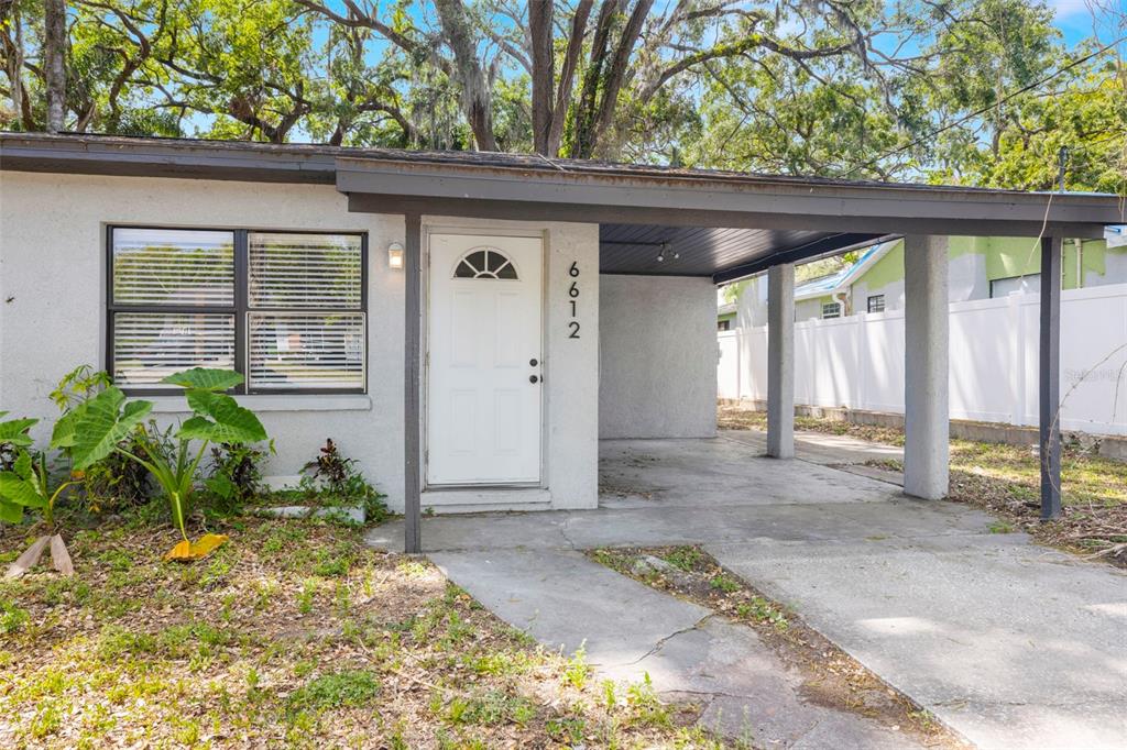 A single-story house exterior features a white front door, a carport, and a front window — 6612 N 23RD STREET, TAMPA, FL