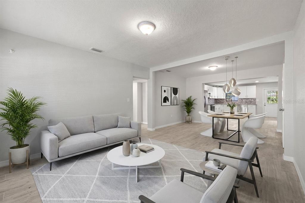 An open-concept living and dining area features light wood-look flooring and modern neutral furniture — 6612 N 23RD STREET, TAMPA, FL