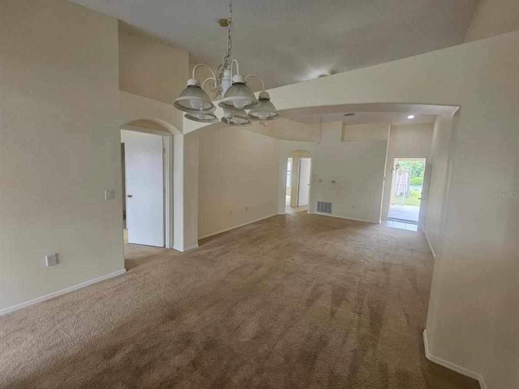 An interior view shows a carpeted dining area with a chandelier and an arched entryway — 13415 FAIRWAY GLEN DRIVE UNIT 203, ORLANDO, FL