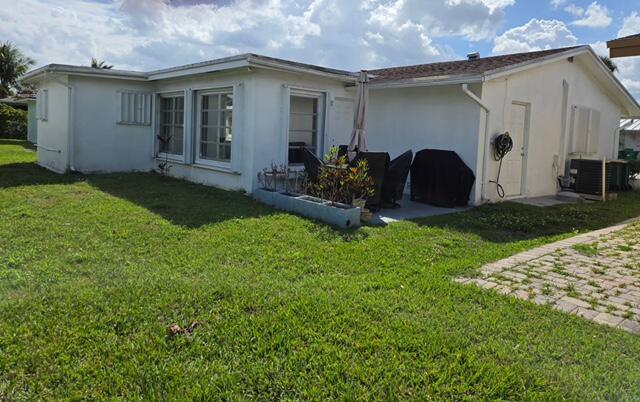 A white single-story house exterior with a grassy yard and a small paved patio area — 4504 NW 43rd Terrace, Tamarac FL 33319, TAMARAC, FL