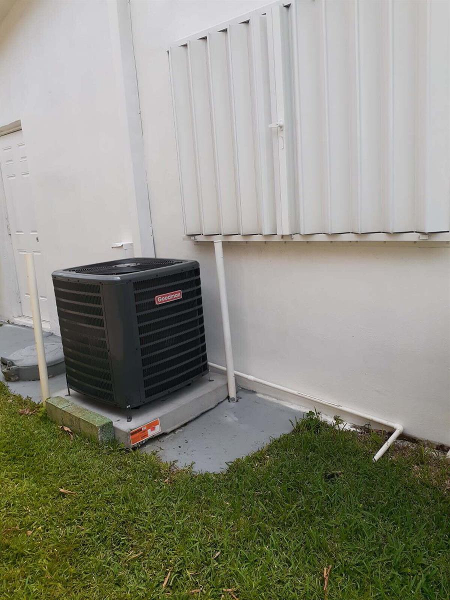 A Goodman air conditioning unit sits on a concrete pad outside a white building — 4504 NW 43rd Terrace, Tamarac FL 33319, TAMARAC, FL