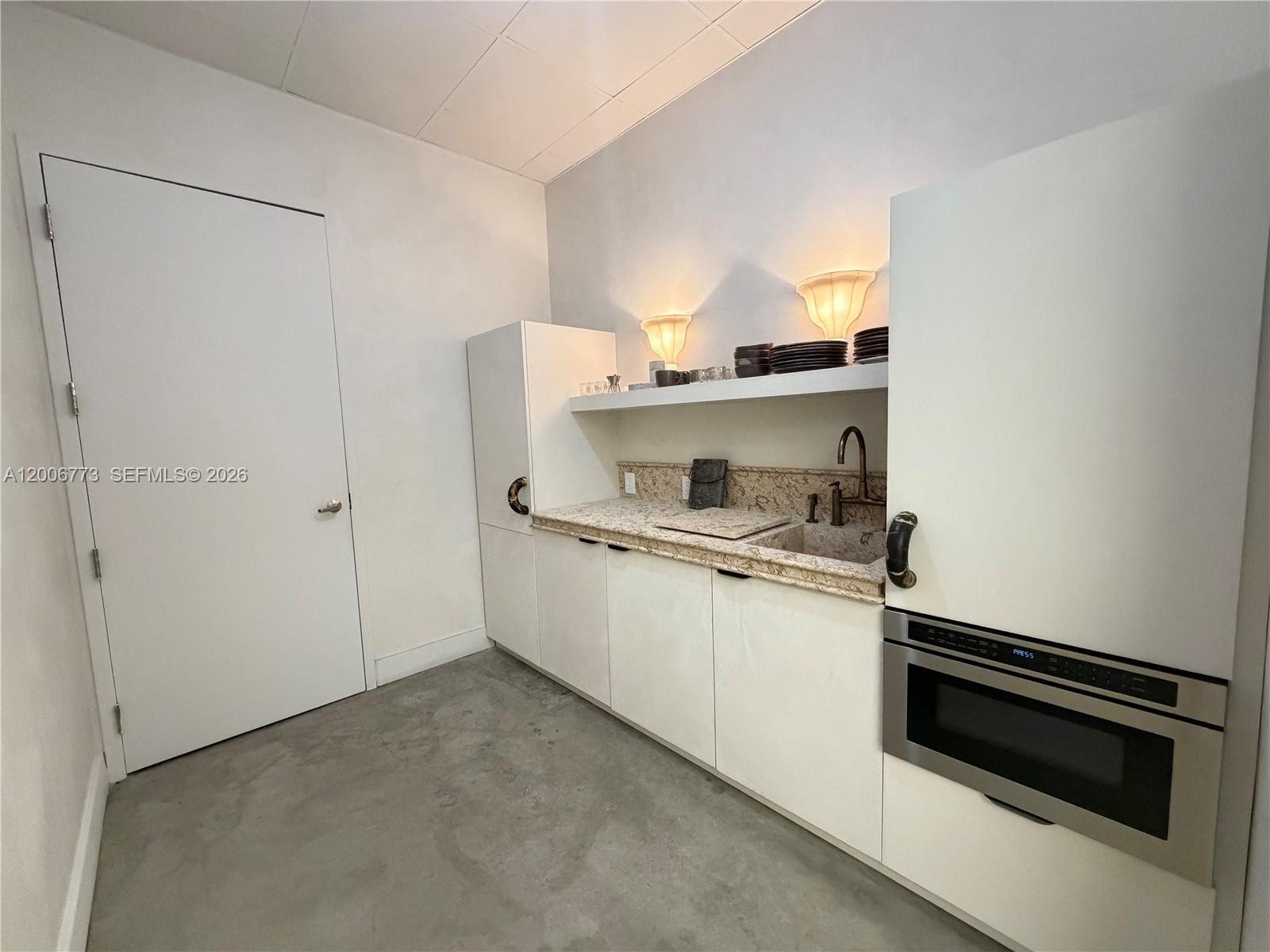 A kitchenette features white cabinets, a granite countertop, a sink, and a built-in microwave — 3015 Grand Ave # 0210, Miami FL 33133, MIAMI, FL