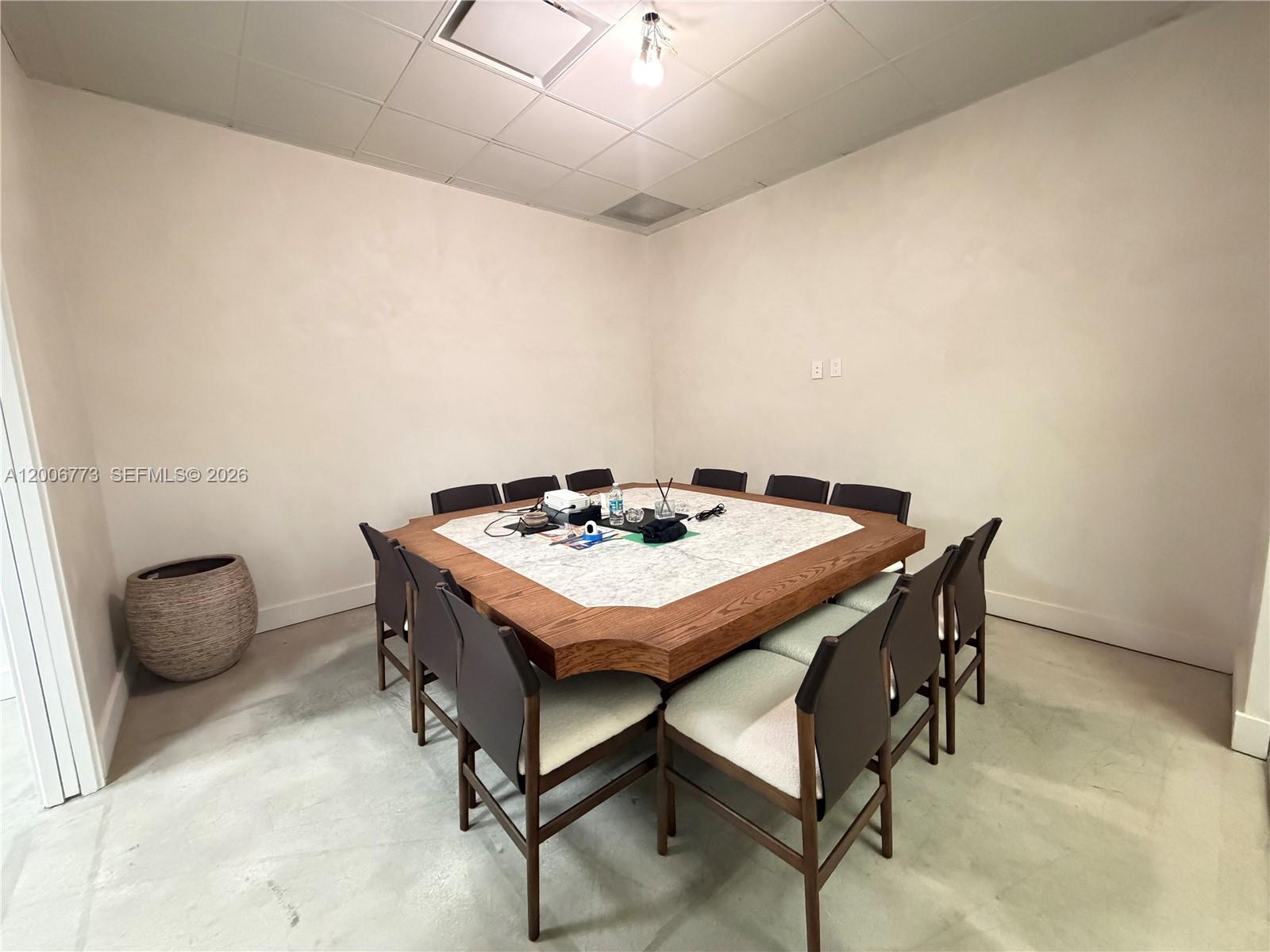 A square conference table with chairs sits in a room with plain walls — 3015 Grand Ave # 0210, Miami FL 33133, MIAMI, FL