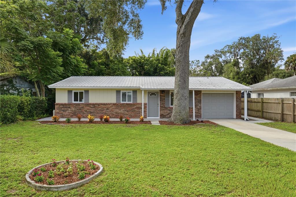 A single-story house with a brick and light-colored siding exterior, a metal roof, and garage — 205 PONCE STREET, NEW SMYRNA BEACH, FL