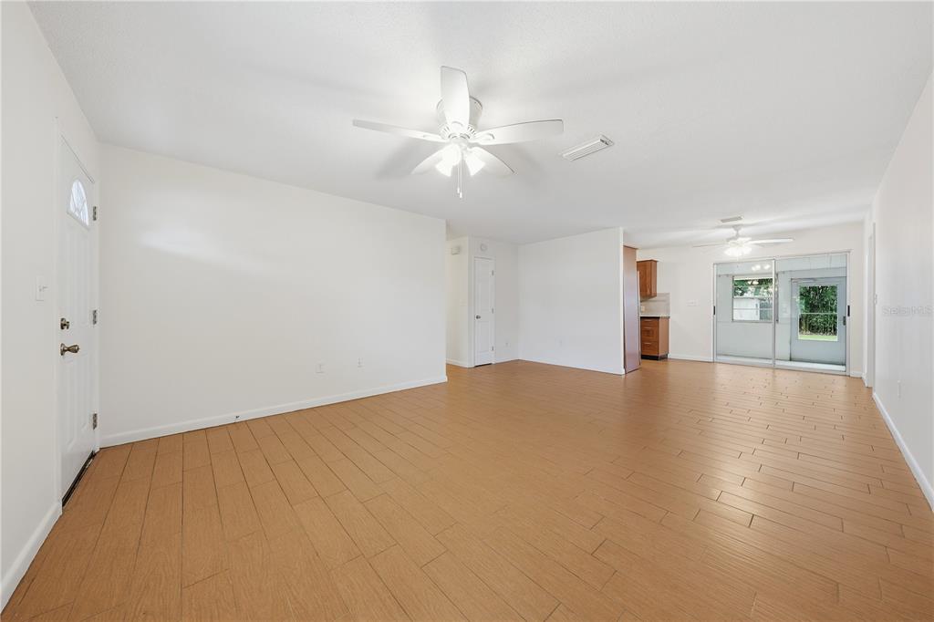 A living room with light wood-look flooring, a gray sofa, two leather chairs, and a television — 205 PONCE STREET, NEW SMYRNA BEACH, FL