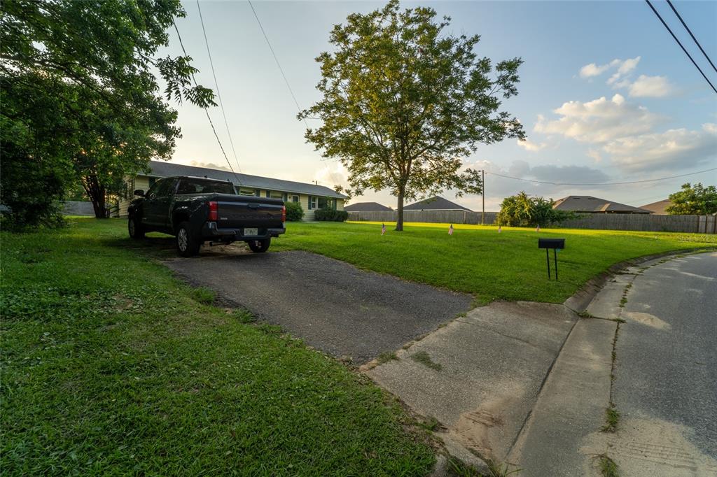 A black pickup truck is parked on a driveway next to a house and lawn — 6915 KLONDIKE ROAD, PENSACOLA, FL
