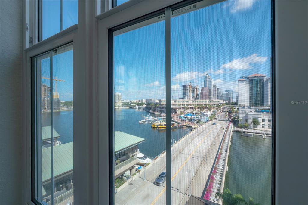A living room features light wood floors, a ceiling fan, and windows overlooking a waterfront — 700 S HARBOUR ISLAND BOULEVARD UNIT 713, TAMPA, FL