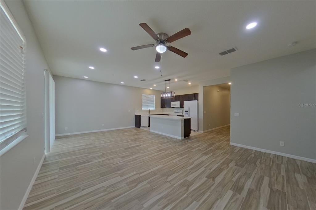 An open-concept kitchen and living area features light wood-look tile flooring and recessed lighting — 6317 DOMENICO COURT, GROVELAND, FL