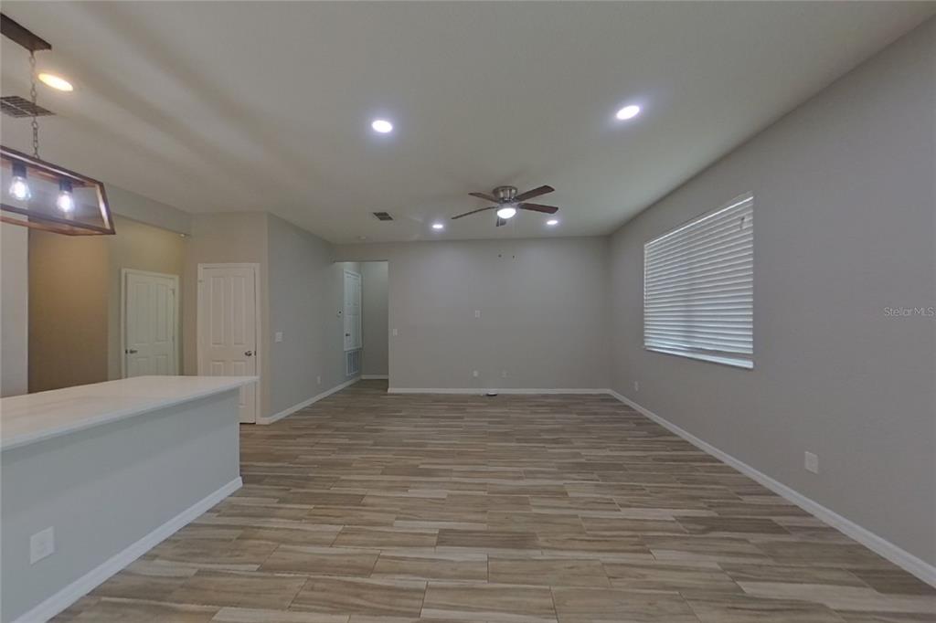 An open-concept living room features light gray walls, wood-look tile flooring, and a ceiling fan — 6317 DOMENICO COURT, GROVELAND, FL