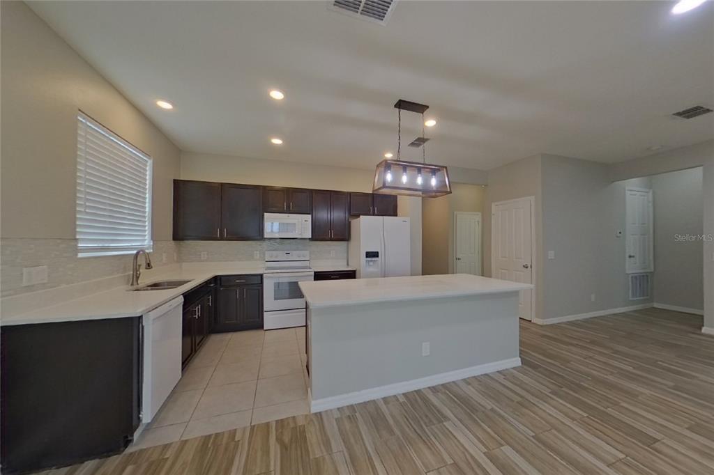 A kitchen features dark wood cabinets, white appliances, a center island, and light-colored tile flooring — 6317 DOMENICO COURT, GROVELAND, FL