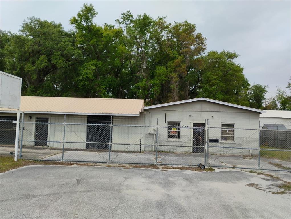 A single-story commercial building with a metal roof sits behind a chain-link fence — 934 NW 17TH AVENUE, OCALA, FL