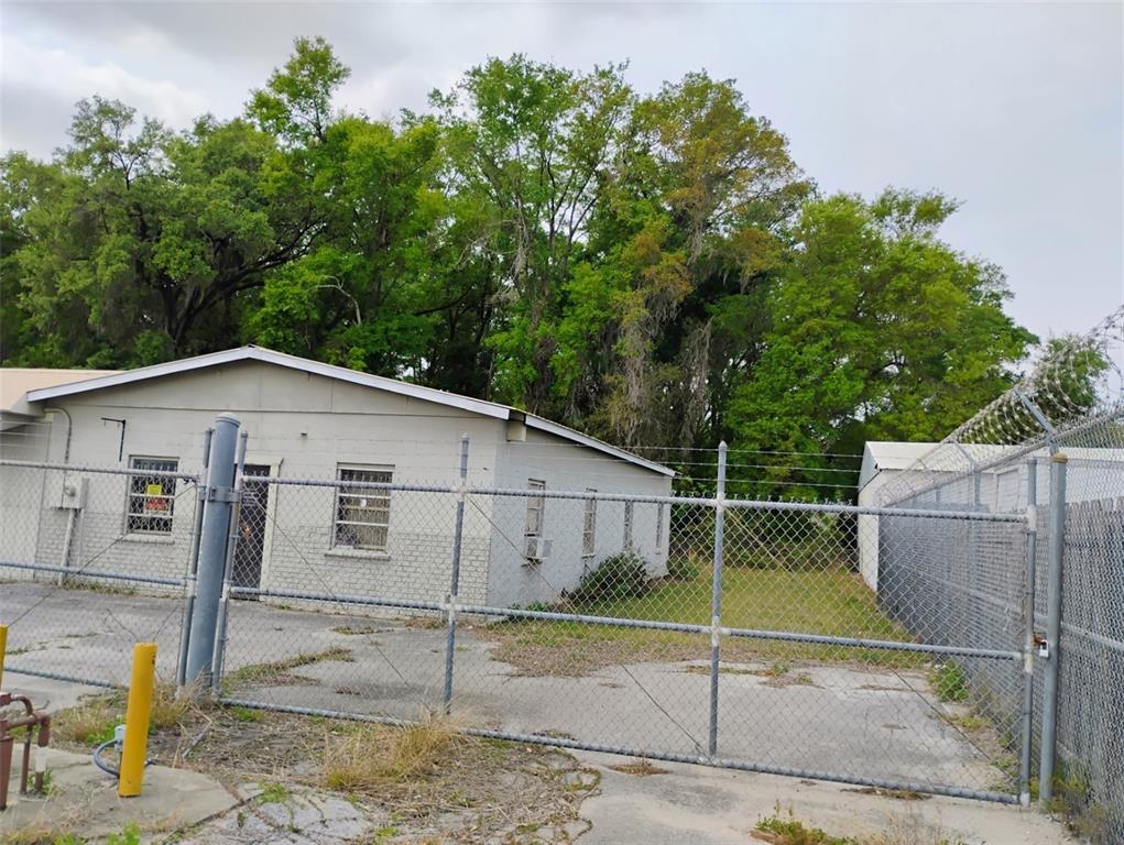 A chain-link fence encloses a paved lot in front of a single-story concrete building — 934 NW 17TH AVENUE, OCALA, FL