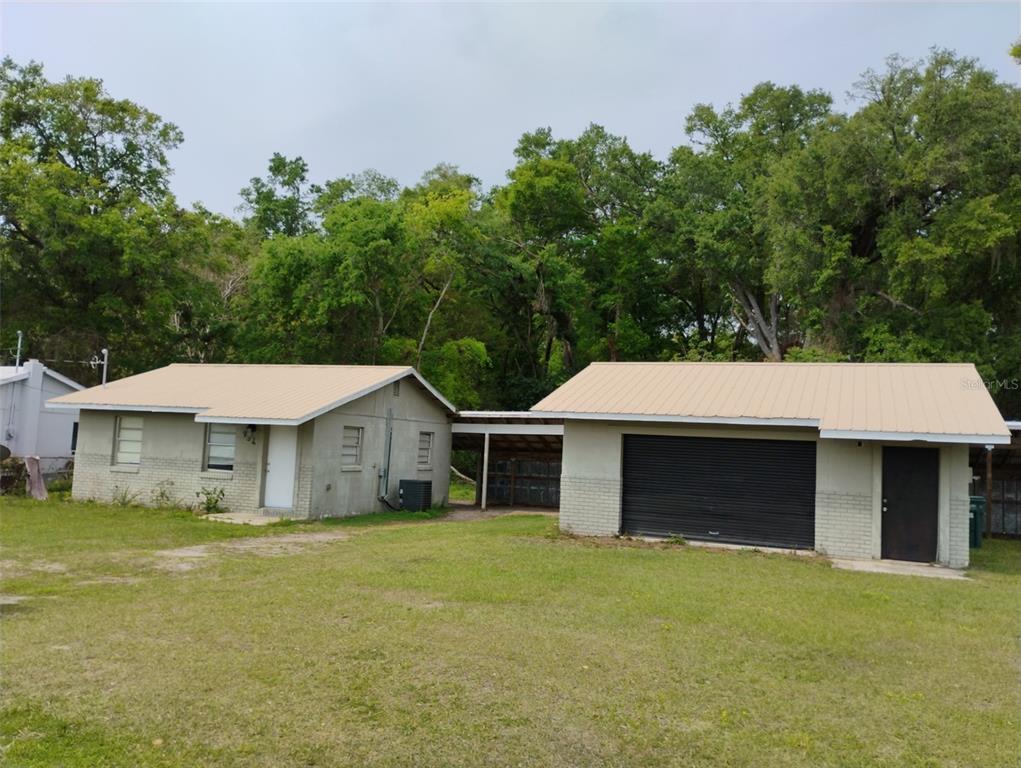 A small, light-colored house with a metal roof and an attached garage connected by breezeway — 934 NW 17TH AVENUE, OCALA, FL