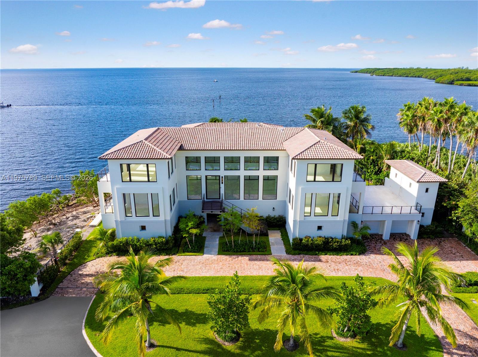 An aerial view shows a large, multi-story waterfront house with a brick driveway and palm trees — 650 Lugo Ave, Coral Gables FL 33156, CORAL GABLES, FL