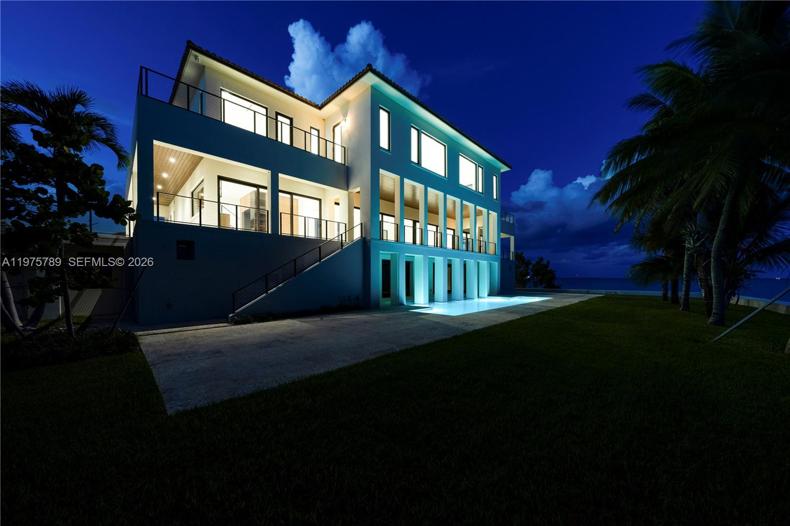 A modern multi-story house with a pool and balconies at night — 650 Lugo Ave, Coral Gables FL 33156, CORAL GABLES, FL